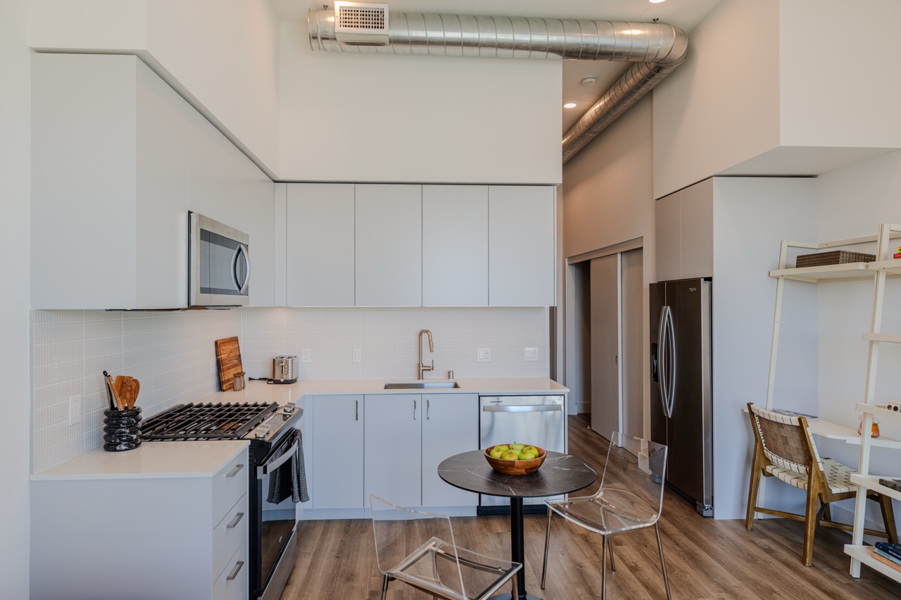 White frameless kitchen with upper cabinetry carried to the ceiling in a loft