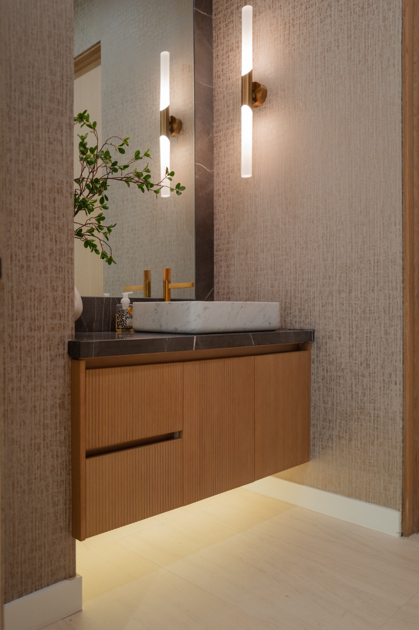 Powder room with a fluted oak floating vanity, stone vessel basin, and brass sconces
