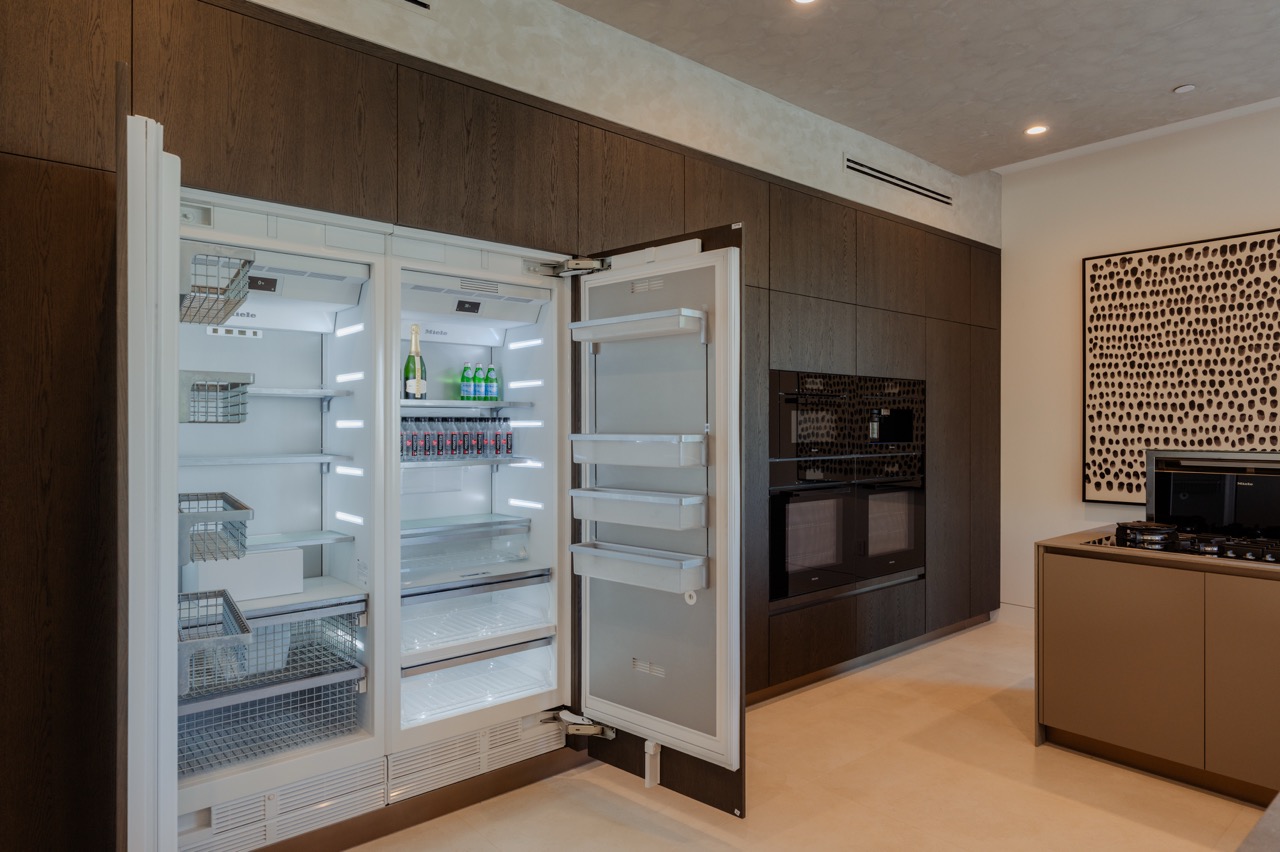 Fully integrated refrigeration behind matching dark oak cabinet fronts, opened to show the interior