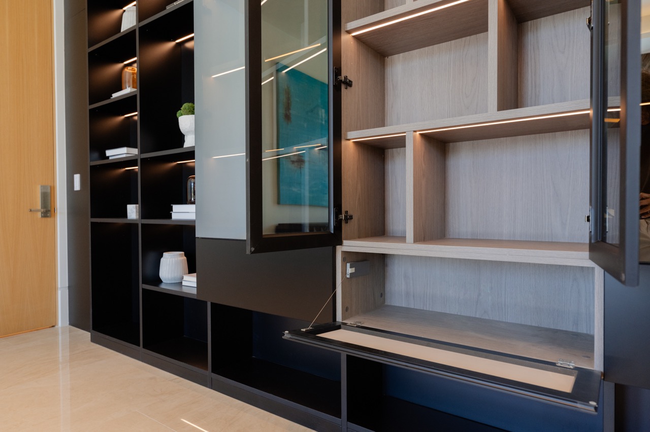 Display cabinetry opened — glass door, drop-down flap and a lit oak interior