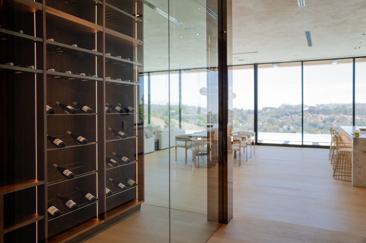 Wine room seen through the glass wall, racking backlit along every column