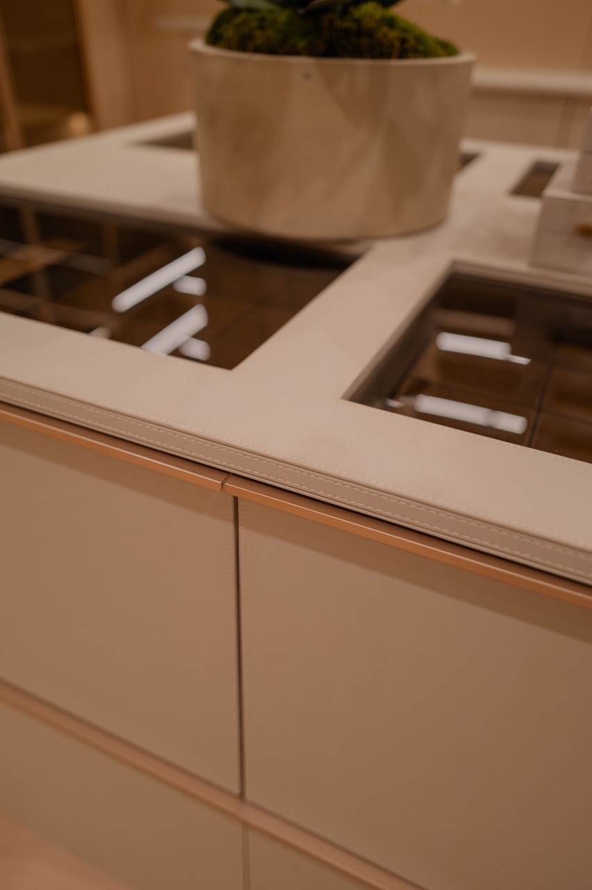 Leather-wrapped island edge with stitched detailing and a glass display top