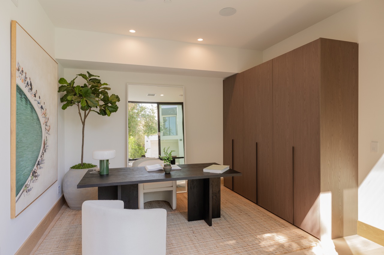 Home office with a full-height walnut storage wall and recessed pulls